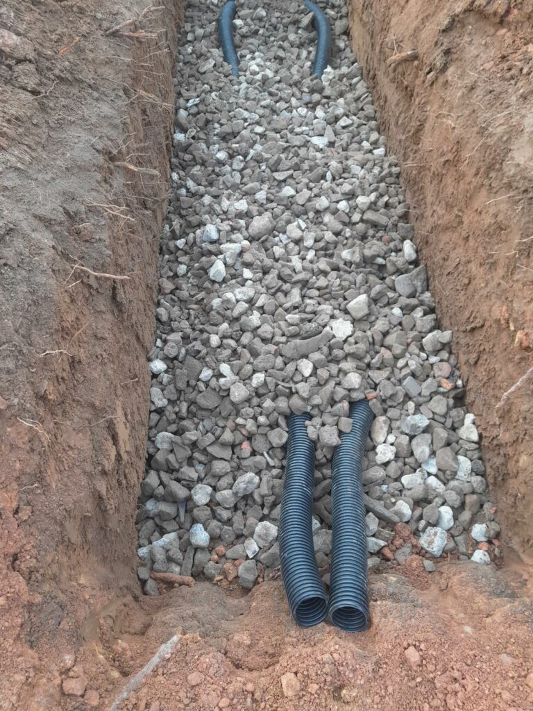 Travaux d’égouttage à Waimes avec pose de canalisations et lit de graviers dans une tranchée